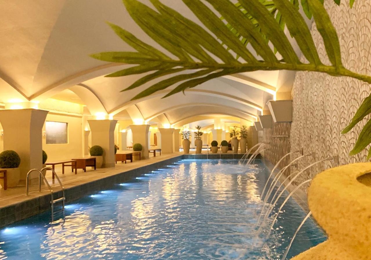 Buona Vitta Gramado Resort & Spa By Gramado Parks Exterior foto The photo shows an indoor swimming pool with a serene and elegant atmosphere. The pool has a calm blue water surface, illuminated by soft lights along its edges. The architectural design features arches in the ceiling, creating an open and spacious f