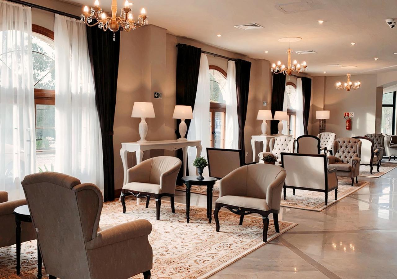 Buona Vitta Gramado Resort & Spa By Gramado Parks Exterior foto The photo depicts a stylish and sophisticated lounge area. It features several elegant chairs and sofas, arranged around small tables on a decorative rug. The room is well-lit with natural light coming in through large windows dressed with flowing wh