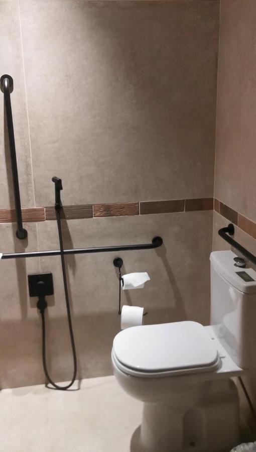 Buona Vitta Gramado Resort & Spa By Gramado Parks Exterior foto The photo shows a bathroom equipped with grab bars for accessibility. The walls are tiled in a neutral color, and there is a toilet on the right side of the image. Two rolls of toilet paper are positioned near the toilet, and there are additional ins