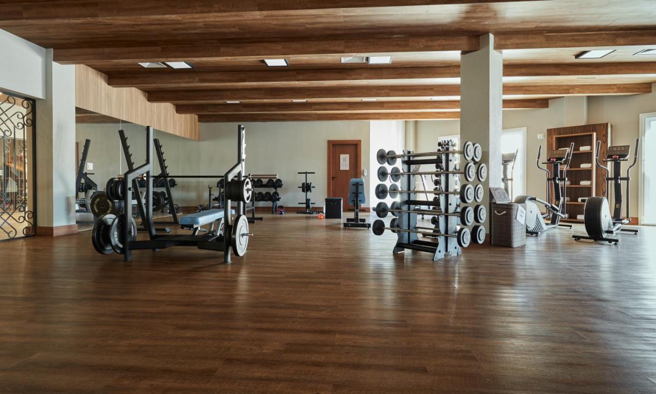 Buona Vitta Gramado Resort & Spa By Gramado Parks Exterior foto The photo shows a spacious gym with a wooden floor and wooden ceiling beams. Various pieces of gym equipment are visible, including weight benches and racks with weights. On one side, there are free weights organized on a rack, while other equipment 
