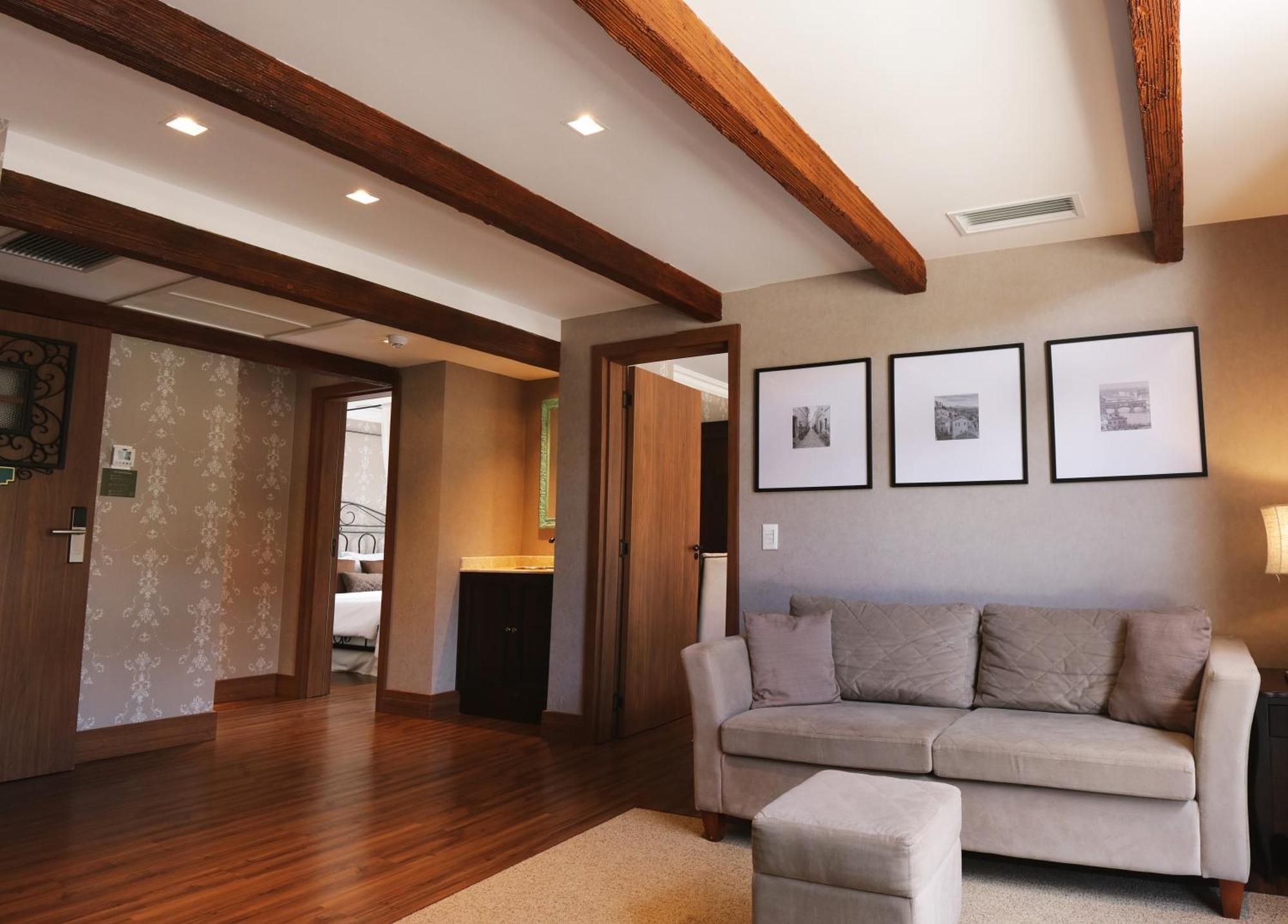 Buona Vitta Gramado Resort & Spa By Gramado Parks Exterior foto The photo showcases a modern living space with a cozy and well-lit atmosphere. There are wooden beams visible on the ceiling, adding a rustic touch. The flooring is a warm-toned wood, contributing to the inviting feel of the room. 

On one side, ther