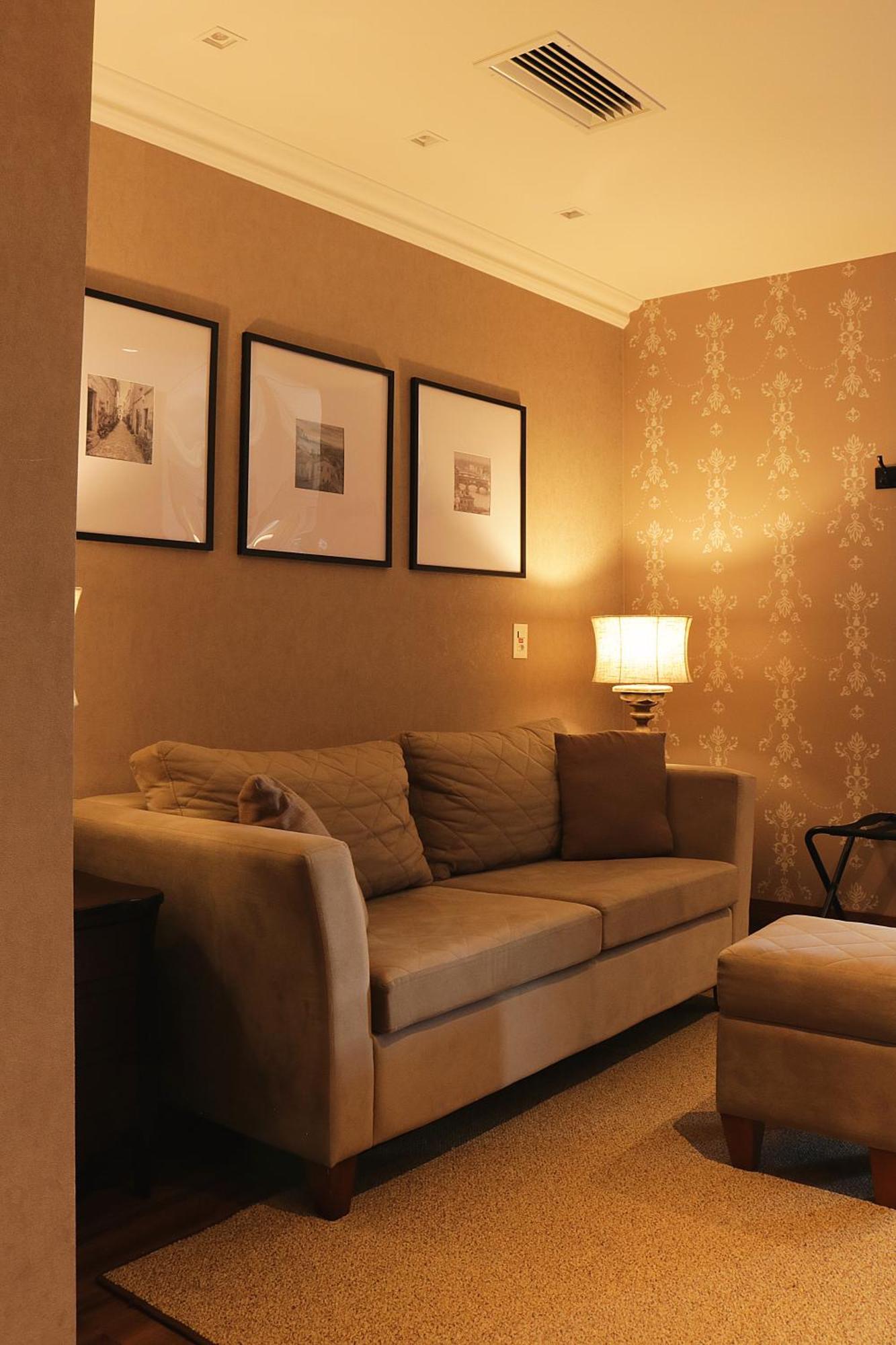 Buona Vitta Gramado Resort & Spa By Gramado Parks Exterior foto The photo shows a cozy living room setting. There is a light-colored sofa adorned with several cushions, positioned against a wall that has a subtle pattern. Above the sofa, there are three framed artworks or photographs hanging on the wall. To the s